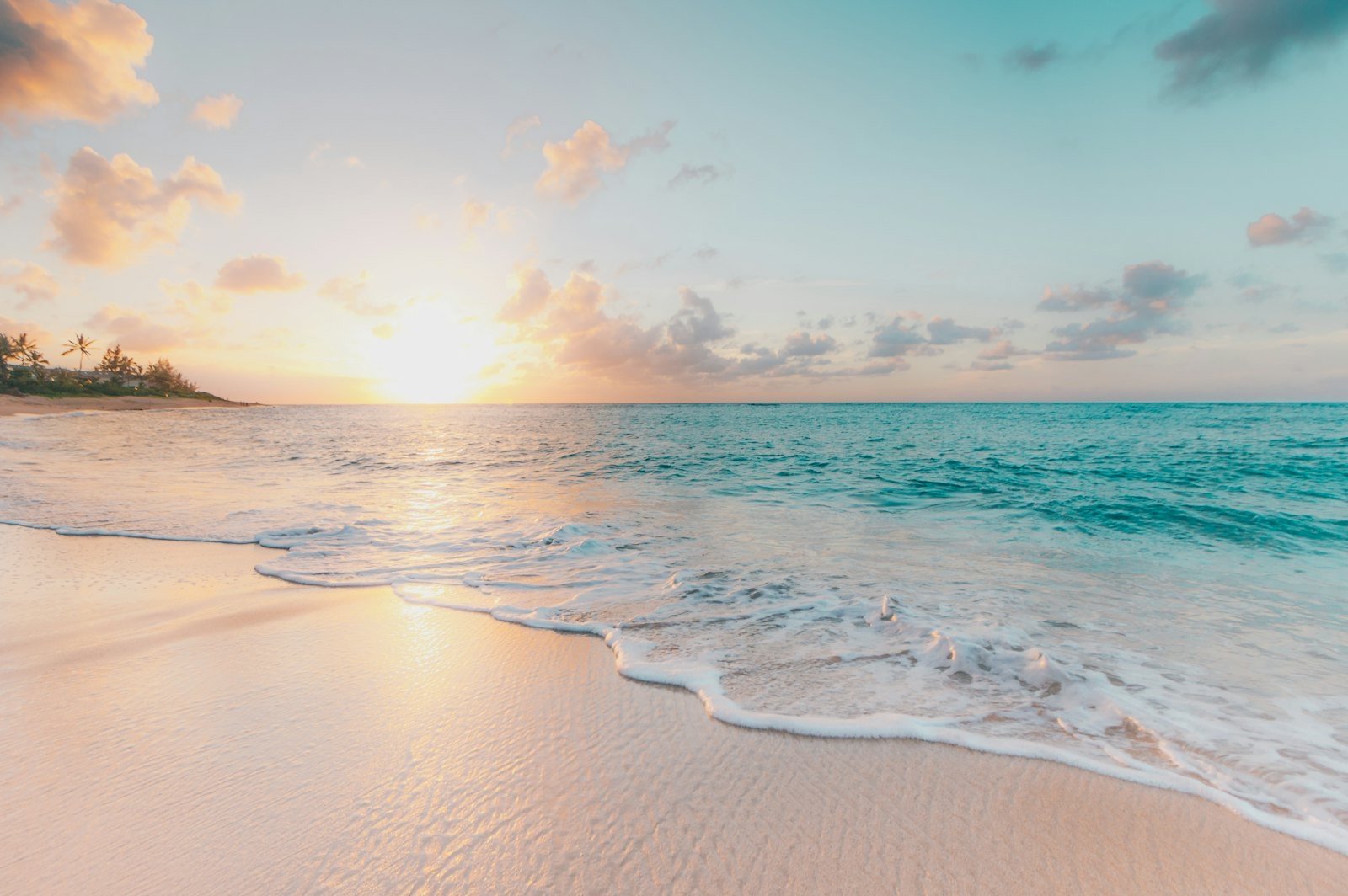 Turquoise sea washing onto a white sand beach at sunset