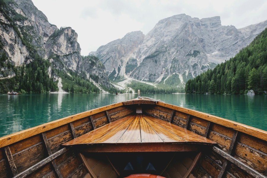 Wooden boat on an emerald alpine lake surrounded by mountains